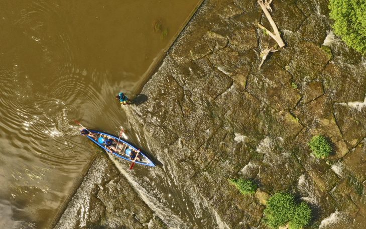 Ein Boot fährt auf dem Wasser, während eine Person am Ufer steht.
